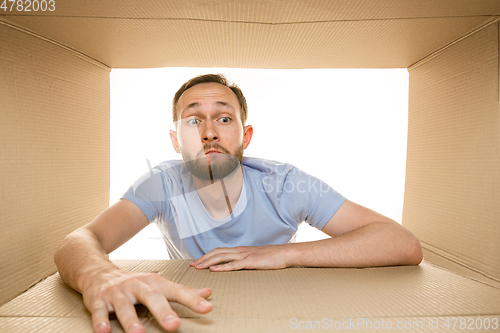 Image of Young man opening the biggest postal package isolated on white