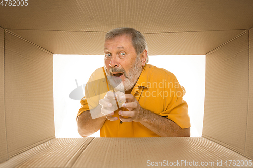 Image of Senior man opening the biggest postal package isolated on white