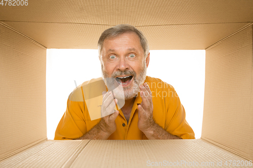 Image of Senior man opening the biggest postal package isolated on white