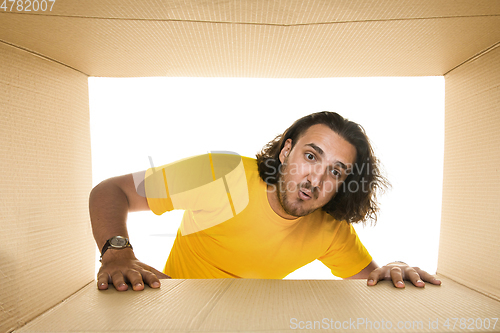 Image of Young man opening the biggest postal package isolated on white