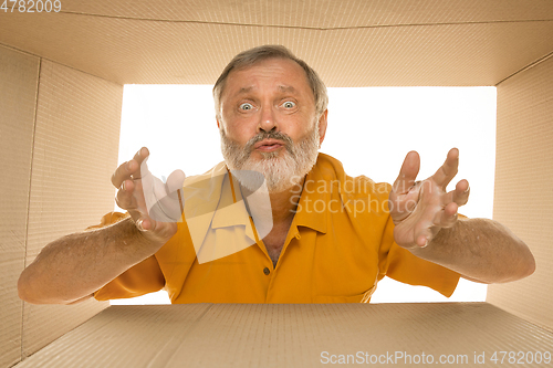 Image of Senior man opening the biggest postal package isolated on white