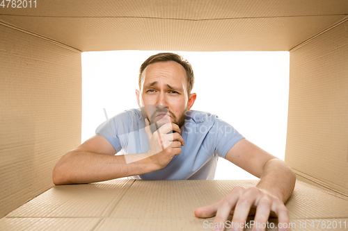 Image of Young man opening the biggest postal package isolated on white