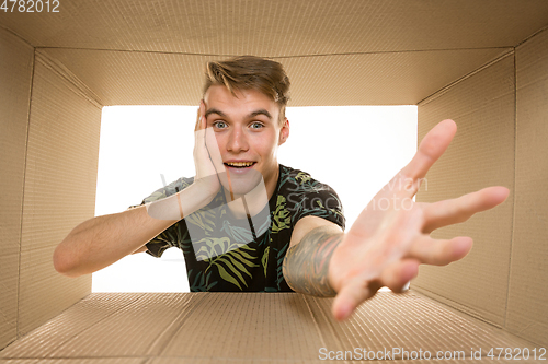 Image of Young man opening the biggest postal package isolated on white