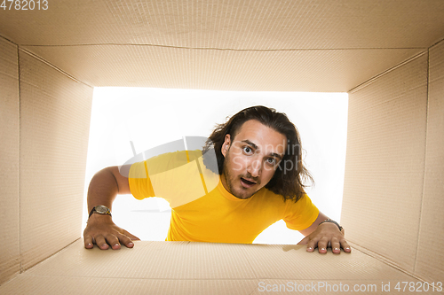 Image of Young man opening the biggest postal package isolated on white