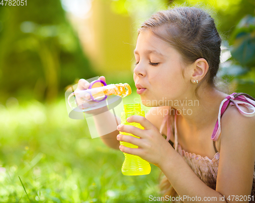 Image of Little girl is blowing a soap bubbles