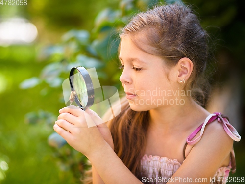 Image of Young girl is looking at flower through magnifier