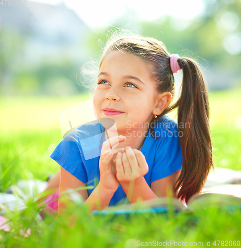 Image of Portrait of a little girl laying on green grass
