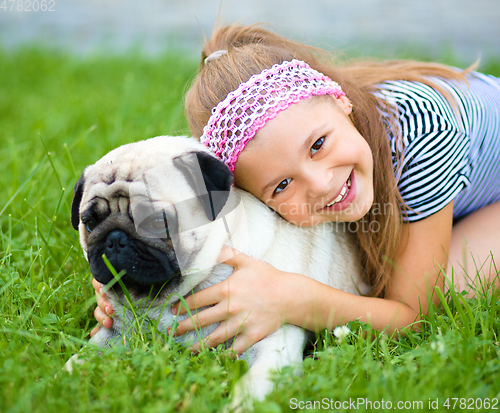 Image of Little girl and her pug dog on green grass