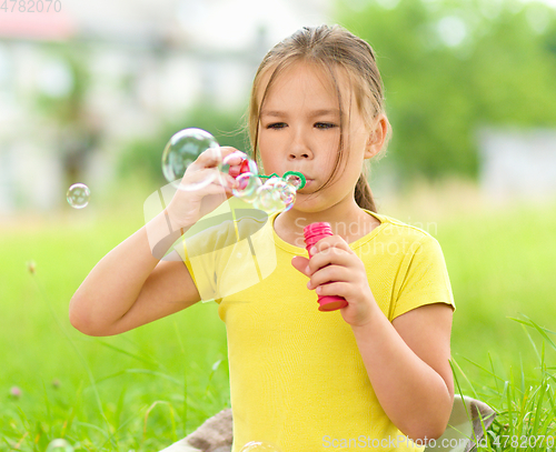 Image of Little girl is blowing a soap bubbles