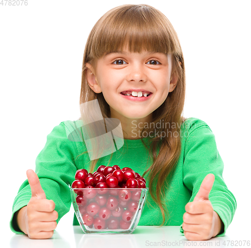 Image of Cute girl is eating cherries showing thumb up sigh