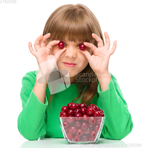 Image of Cute girl is eating cherries