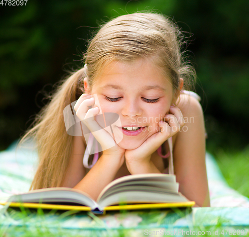 Image of Little girl is reading a book outdoors