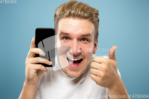 Image of Caucasian young man\'s half-length portrait on blue background