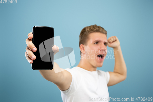Image of Caucasian young man\'s half-length portrait on blue background
