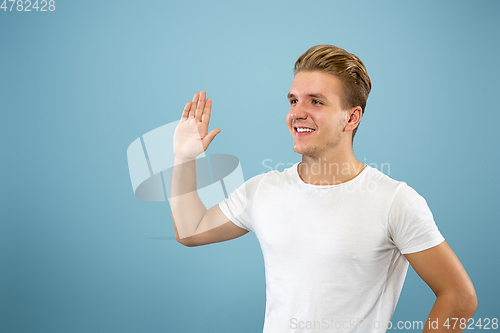 Image of Caucasian young man\'s half-length portrait on blue background