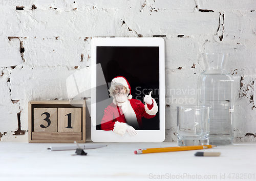 Image of Happy Christmas Santa Claus shows thumb up in tablet