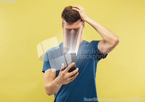 Image of Young man engaged by gadget and social media isolated on yellow background