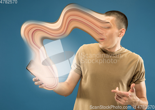 Image of Young man engaged by gadget and social media isolated on blue background