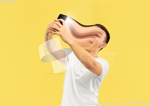 Image of Young man engaged by gadget and social media isolated on yellow background