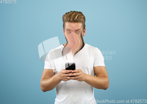 Image of Young man engaged by gadget and social media isolated on blue background