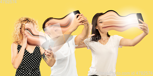 Image of Young people engaged by gadget and social media isolated on yellow background