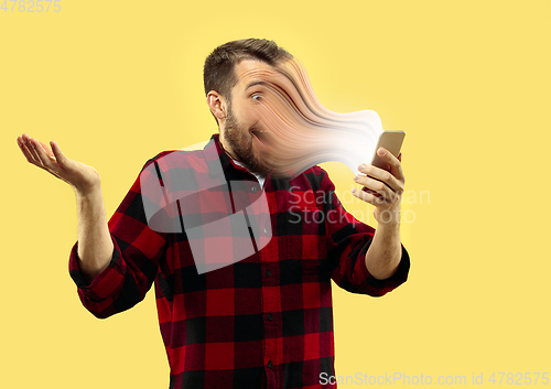 Image of Young man engaged by gadget and social media isolated on yellow background