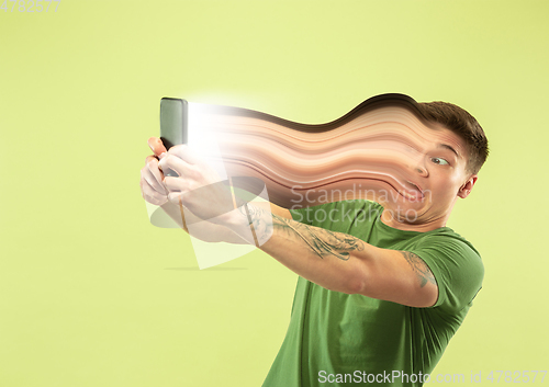 Image of Young man engaged by gadget and social media isolated on green background