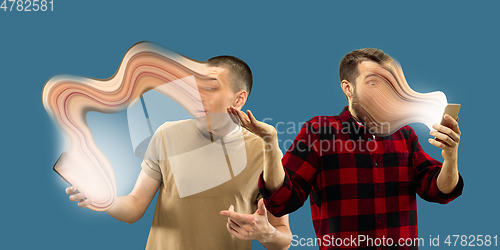 Image of Young men engaged by gadget and social media isolated on blue background