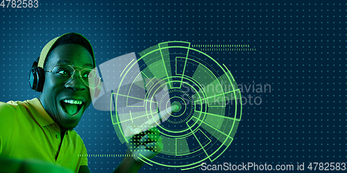 Image of Young african-american man\'s touching virtual reality in neon light