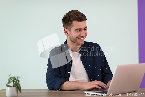 Image of Smiling young man freelancer using laptop studying online working from home