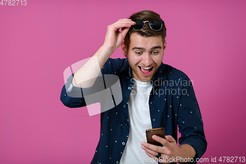 Image of a young man wearing a blue shirt and sunglasses using a smartphone