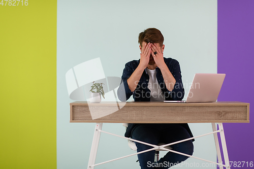 Image of disappointed and annoyed man sitting at a table and looking at a laptop