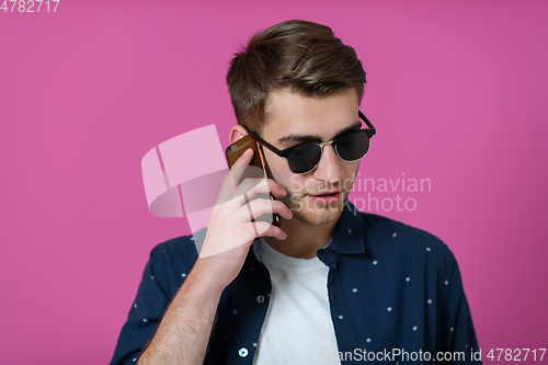 Image of a young man wearing a blue shirt and sunglasses using a smartphone
