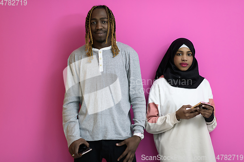 Image of young african american couple laughing using smartphones apps isolated on pink studio background