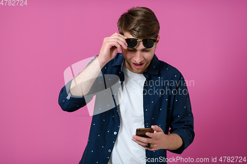 Image of a young man wearing a blue shirt and sunglasses using a smartphone