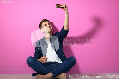 Image of man sitting on the floor of the house and using the phone