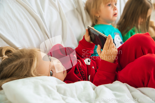 Image of Little girls in soft warm pajamas playing at home