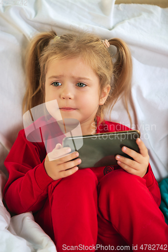 Image of Little girl in soft warm pajama playing at home