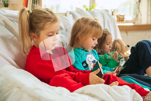 Image of Little girls in soft warm pajamas playing at home