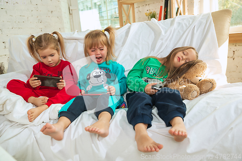 Image of Little girls in soft warm pajamas playing at home