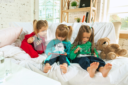 Image of Little girls in soft warm pajamas playing at home