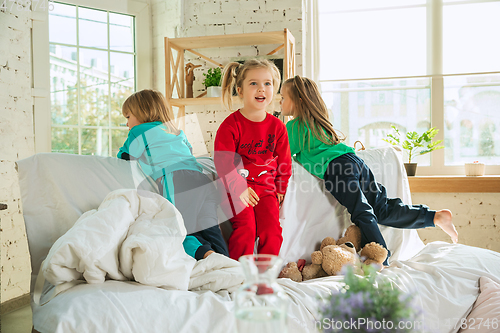 Image of Little girls in soft warm pajamas playing at home