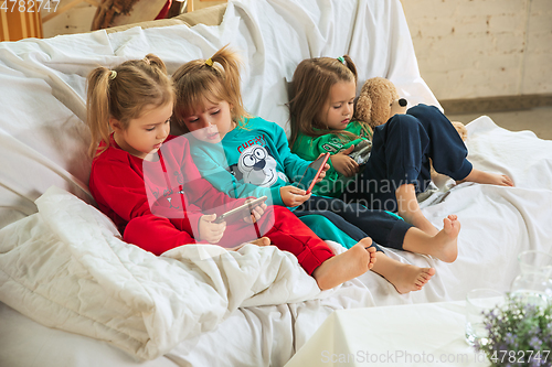 Image of Little girls in soft warm pajamas playing at home