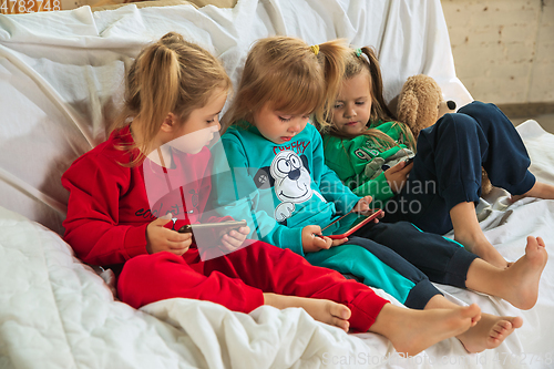 Image of Little girls in soft warm pajamas playing at home