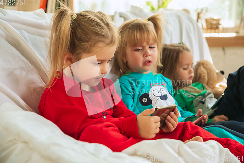 Image of Little girls in soft warm pajamas playing at home