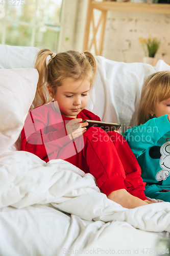 Image of Little girls in soft warm pajamas playing at home