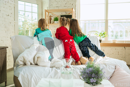 Image of Little girls in soft warm pajamas playing at home