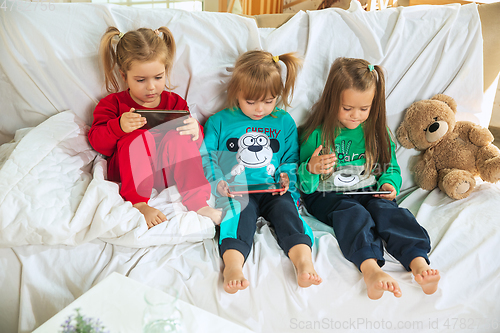 Image of Little girls in soft warm pajamas playing at home