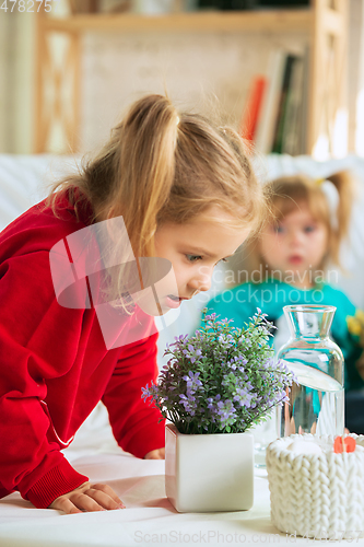 Image of Little girls in soft warm pajamas playing at home