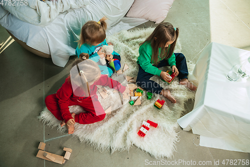 Image of Little girls in soft warm pajamas playing at home